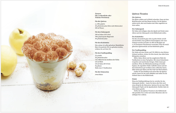 Ein Rezept aus meinem neuen Kochbuch. Weißer Hintergrund. In der Mitte ein großes Weckglas. Darin zerkleinerte Kekse, gekochte Quittenstücke, darauf Sahnequark und eine gespritzte Krone aus Sahnequark. Zuletzt Kakao – darüber gesiebt.