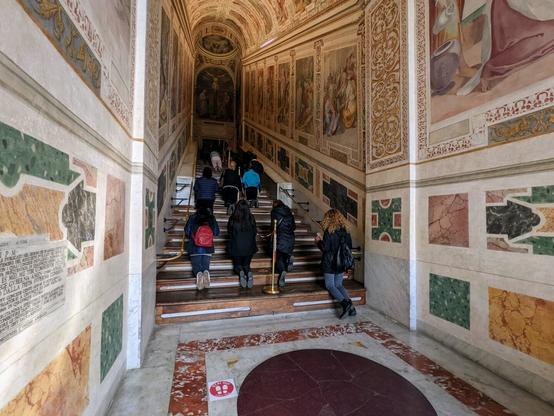A series of marble stairs covered in wooden stairs with people climbing them on their knees
