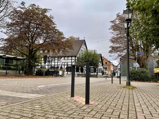 zwei Fahrradständer; dahinter das Fachwerkhaus des Wirtshaus; rechts ist das Straßenschild "Klostermarkt" zu sehen