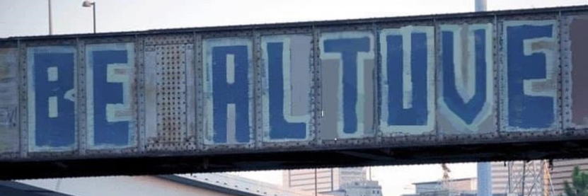 Graffiti on railroad trundle over highway just north of downtown Houston.  Blue block letters with some white for accent that reads "Be Altuve".  Refers to demure but confident Jose Altuve, star hitter and shortstop of the Houston Astros baseball team. US immigrant from Venezuela. Bilingual.