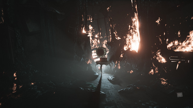 Zrzut ekranu z gry "Layers of Fear" przedstawiający bliżej nieokreślne pomieszczenie, stojące w krwisto-czerwonych płomieniach. Pośrodku pomieszczenia, na podłodze wykonanej z cyklinowanego drewna stoi niewielki, ozdobny stolik z jasno-brązowego drewna z blatem wykonanym z białego marmuru, na którym sto gramofon odtwarzający zniekształconą płytę winylową. Z sufitu zwisają girlandy roztapiającej się czarnej, bezkształtnej masy, która spływa również po ścianach na podłogę zastygając niczym magma i pochłaniając wszystko na swojej drodze niczym pasożytniczy organizm. Pomimo płomieni buchających z dziur w ścianach oraz z czarnej masy, nie oświetlają one wnętrza tego pomieszczenia - robi to za to tajemnicze źródło trupio-bladego światła wydobywającego się zza gramofonu.