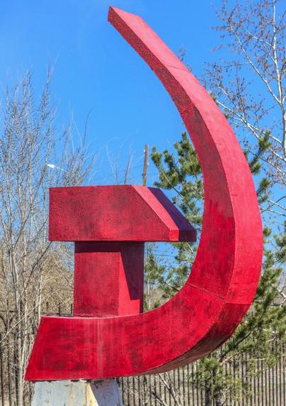 A bright red statue of a Soviet Hammer and Sickle contrasted against the beautiful blue Kazakh sky