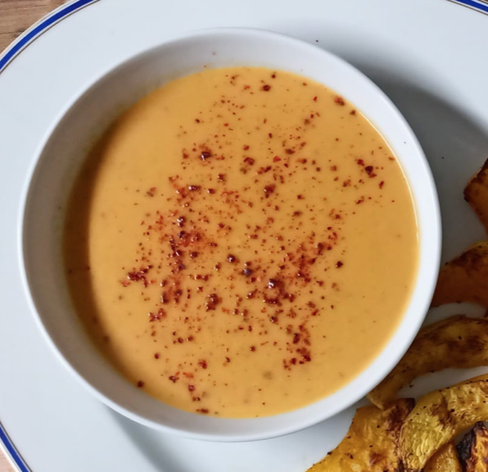 Die fertige Kürbissuppe in einer Schale, mit Chilipulver bestreut