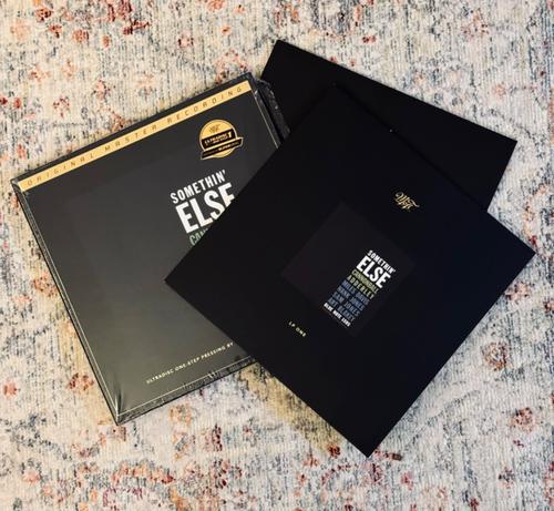 Photo of a record box set, contents splayed out across a pale rug. 

The box and album jackets are jet black with white, green, and blue text reading, ‘Somethin’ Else,’ ‘Cannonball Adderley,’ before then listing the other musicians.