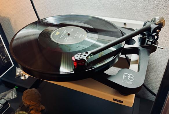 Photo of a black vinyl record spinning on the skeletal frame of a Rega P8 turntable.