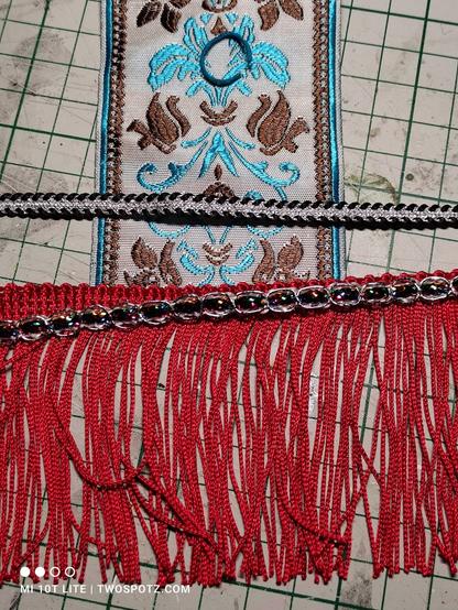 Broad pale patterned ribbon with a red frill trim underneath it.