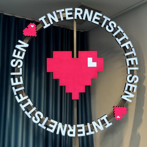 lighted sign of Internetstiftelsen in white and pixel art heart in pink