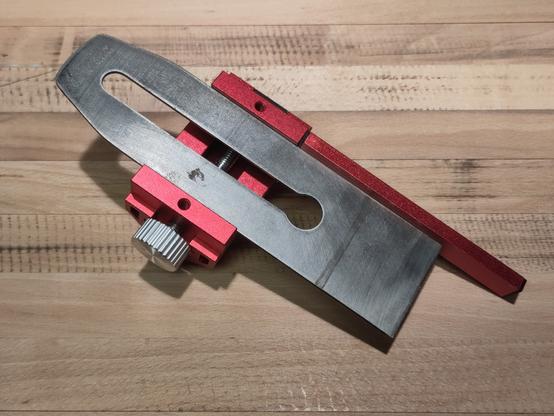Lame de rabot sur un guide en aluminium rouge.