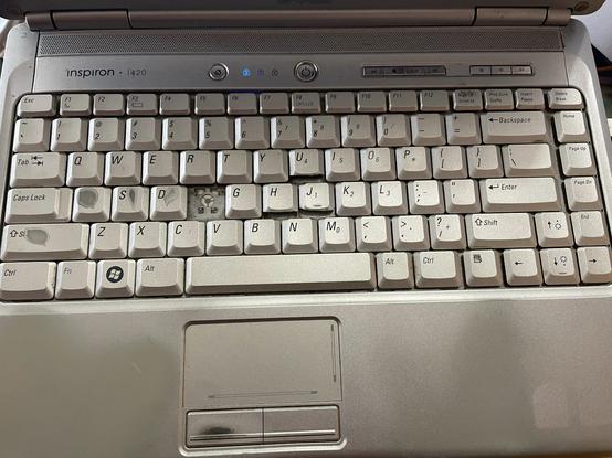 A Dell Inspiron 1420 keyboard, showing extreme signs of wear and physical mutilation.