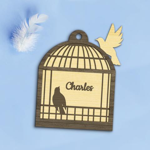 Décoration de de Noël en bois découpé et gravé représentant une cage ouverte d'où deux oiseaux s'envolent. Elle est personnalisée avec le prénom de votre choix. A retrouver dans notre boutique en ligne : ernestine-etcie.fr