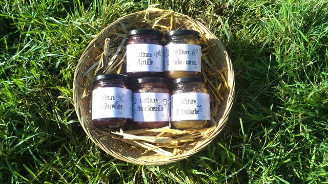Pots de confiture dans un petit panier sur une petite couche de paille moelleuse, le panier etant lui meme posé dans l herbe verte pétant