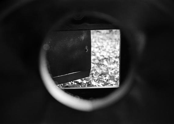 Black and white image looking through the stove pipe of a small evaporator used for making maple syrup.