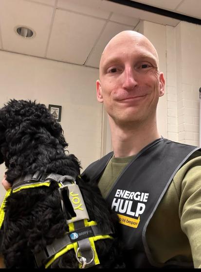 Joy the black Doodle visiting the headquarters of Energy Help. Here she’s manning the phone as her human is distracted by a selfie.