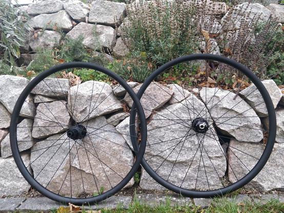 schwarze 28 Zoll Laufräder vor Trockensteinmauer