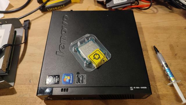The "new" (second-hand) Xeon processor in its antistatic packaging, sitting on top of a Lenovo M93p Tiny.