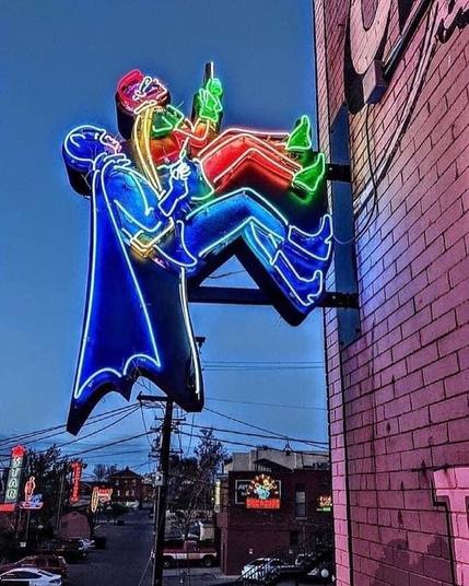 A neon sign of Batman and Robin climbing the wall like they did in the 1960's TV show