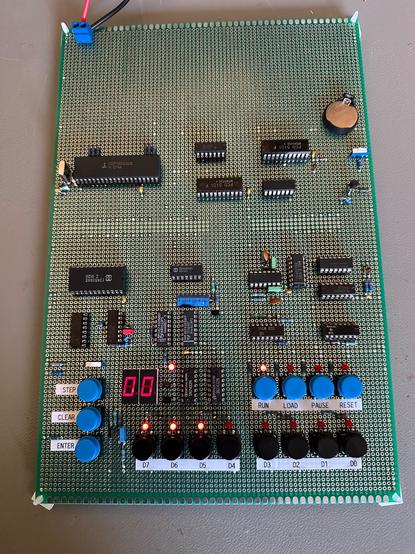 Veroboard with ICs, more or less in the original layout of the Cosmicos. It's running the "flash Q LED" code from the book, with input showing E0 active, LED display showing 00.