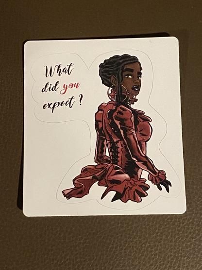 Sticker of Esther for her 3/4 back, in a dark red dress. She turns the head to watch the viewer. On the left, text says “What did you expect?”