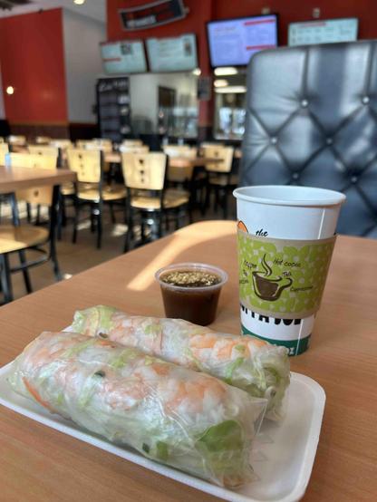 This photo depicts interior of a vietnamese restaurant and spring rolls with hot tea
