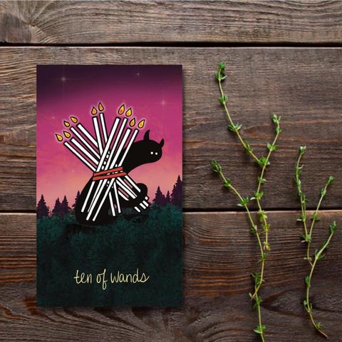 A tarot care on a wooden background. The card is the ten of wands, and is a simple black cartoon like character holding ten long thin candles on its back, as if they are a burden.
