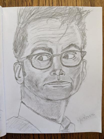 A sketchbook is open to a page featuring a pencil sketch of David Tennant as the Fourteenth Doctor. His hair is spikey, and he's looking to the left.