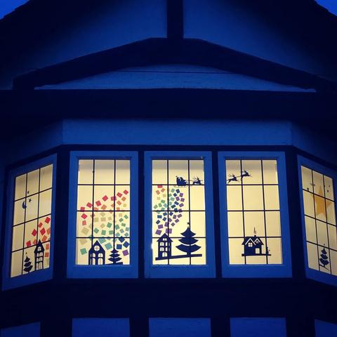 A bay window decorated with Santa in a flying sleigh, trailing a rainbow behind as he flies over several small houses and trees. 📸 Picture: Sustainable St Albans/Lauren Hughes