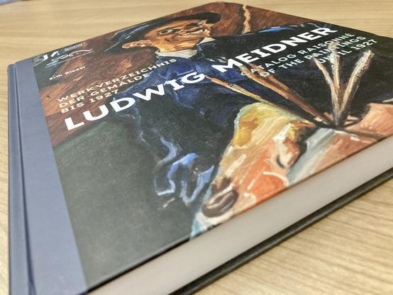 Ein Buch mit dem Titel “Ludwig Meidner. Werkverzeichnis der Gemälde bis 1927” liegt auf einem Holztisch.