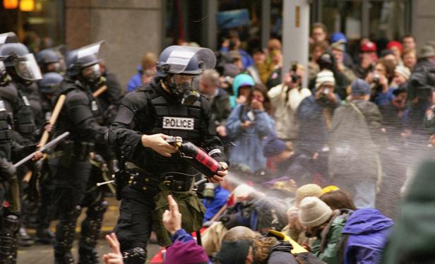 A police officer sprays pepper spray at the crowd. By Steve Kaiser from Seattle, US - WTO protests 10, CC BY-SA 2.0, https://commons.wikimedia.org/w/index.php?curid=4994979