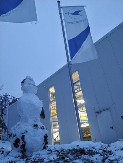 Schneemann vor der Lehrwerkstatt und BWLV-Flaggen.