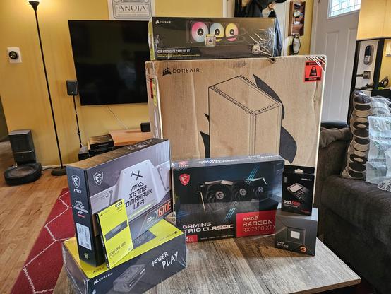 Collection of unopened computer parts: motherboard, psu, cpu, ram, case, cooler, and gpu.