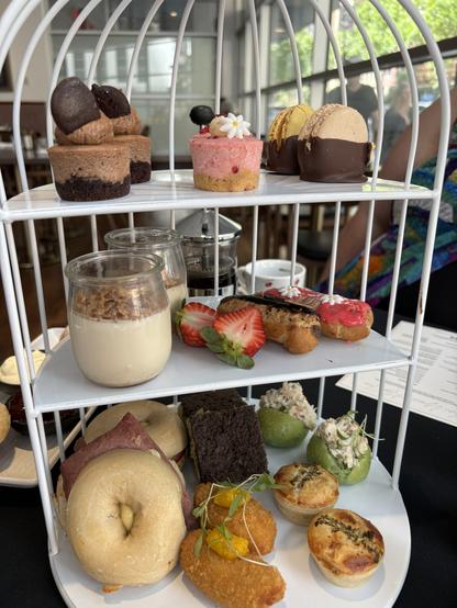 Three-tiered stand with a colourful variety of cakes and savoury treats.
