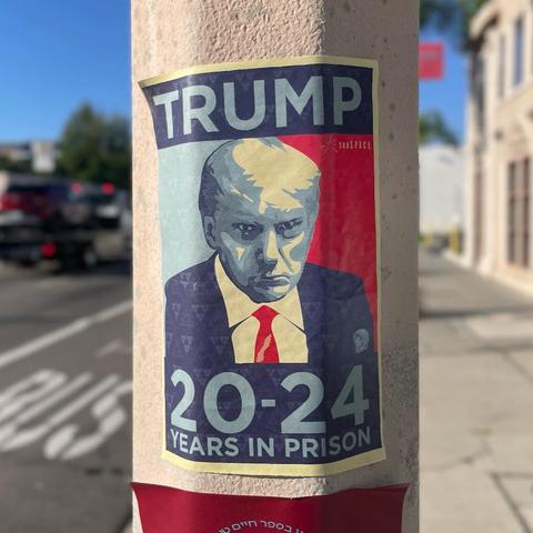 Affiche collé sur un poteau. On voit un portrait de Donald Trump reprenant le style de la campagne d'Obama, avec en gros Trump 2024 et en petit la mention années de prison…