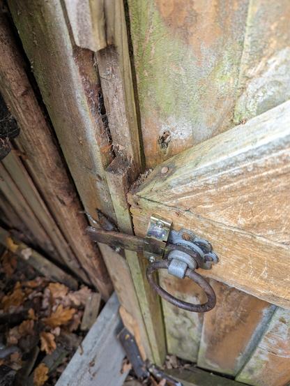 Photo of a broken gate latch that someone has tried to kick in.