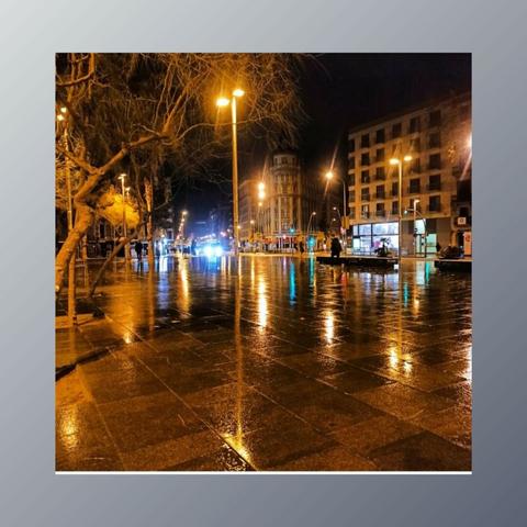 Plaça Universitat mollada per la pluja. Sembla un mirall on reflexen totes les llums