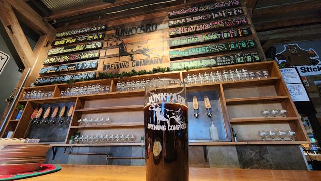 Brew board of Junkyard Brewing with a pint of porter in foreground.