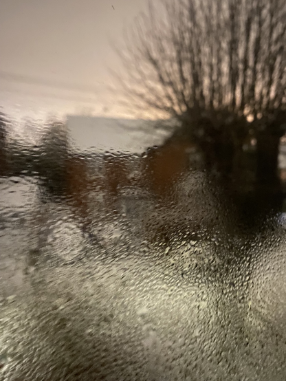 Looking out if the window through condensation to a chilly suburban view
