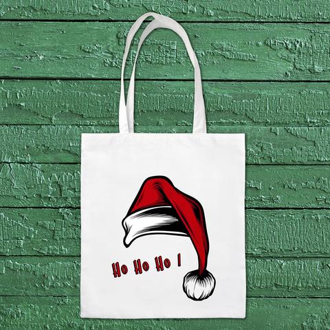 Tote bag de Noël blanc ayant pour motif un gros bonnet de Noël rouge et son pompon et le texte "Ho ho ho". A retrouver dans notre boutique en ligne : ernestine-etcie.fr