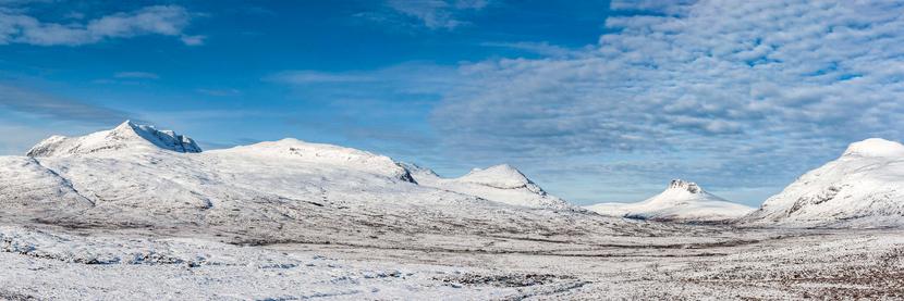 A panoramic snow scene with the hills and mountains just north of Ullapool in Scotland