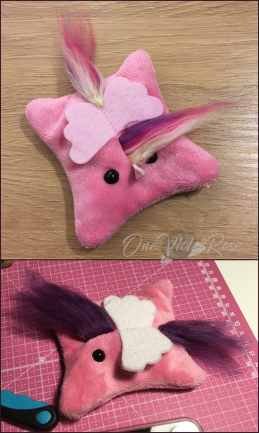 Two beady-eyed beanbags with felt wings and yarn manes. One has a felt horn