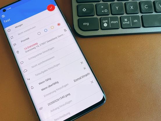 Ein Smartphone mit geöffneter Tasks.org App. Auf dem Bildschirm sind viele Einstellungsoptionen, für eine zu erstellende Aufgabe. Rechts neben dem Smartphone liegt ein Tastatur. Nur ein Teil davon ist sichtbar.