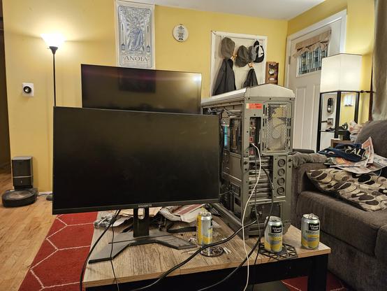 Image of a partially disassembled computer on a cluttered coffee table next to a monitor.