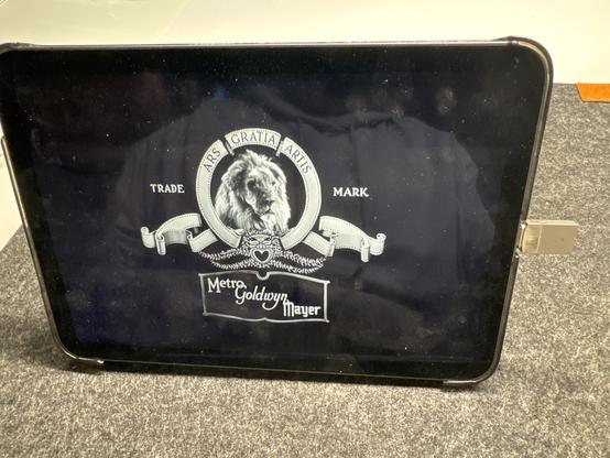 iPad mini verbunden per USB-C mit einem winzigen USB-Stick. Ein Film wird abgespielt . Man sieht das MGM-Logo mit dem Löwen