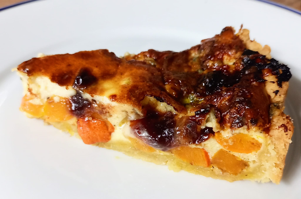 Ein Stück der Quiche auf dem Teller, man sieht die Kürbiswürfel und die leicht zerlaufenden Membrillo-Stücke