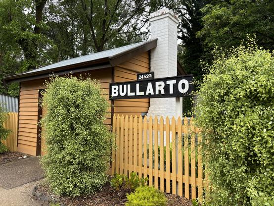 A timber building with chimney at Bullarto Station, bearing a sign naming the station and its altitude of 2,452 feet / 747 metres.