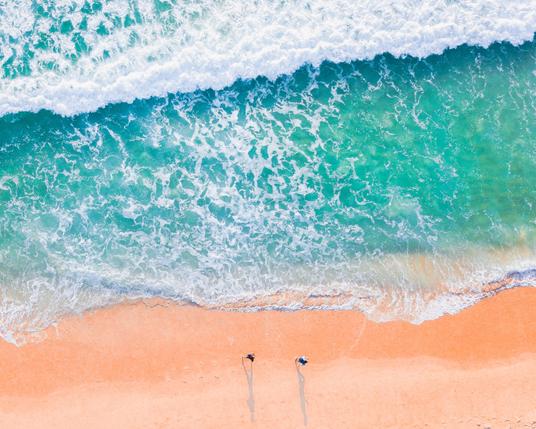2 personnes au bord de la mer, vu d'au-dessus.