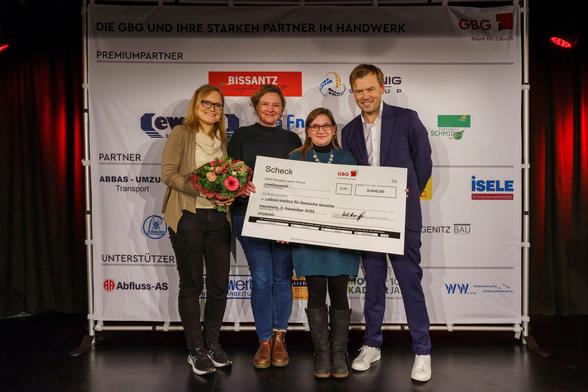 Gruppenfoto vor einer Logowand: Janin Rössel, Elena Schoppa-Briele und Christine Möhrs (alle IDS) nehmen den GBG-Förderpreis zur Weiterführung des Sprach-Checker-Projekts von Christian Franke (GBG) entgegen. Foto: Nikola Haubner