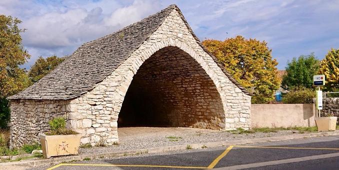 A whole kind of house without windows build out of one broad arc covered with flat stones to keep the rain off. It looks very old and built for some very specific but online purpose. In front is a little sign plus a time table and markings on the road indicating that this is a bus stop