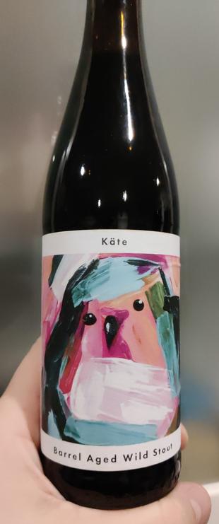 Eine braune glasflasche mit einem Vogel auf dem Etikett der mit wenigen breiten Pinselstrichen farbenfroh gemalt ist.