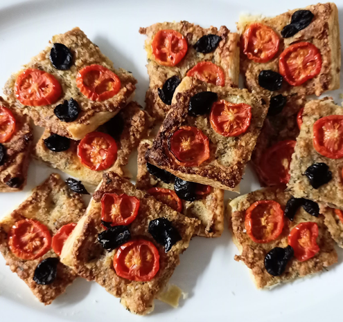Geschnittene Stücken von der  fertigen Tarte mit kleinen Tomatenscheiben und schwarzen Oliven - knusprig gebacken