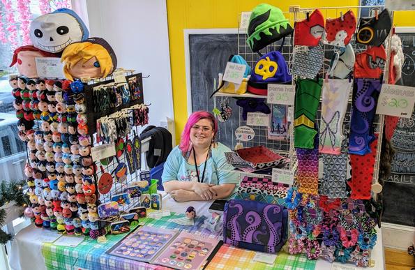 the Pocket Toku booth with a pink-haired Hakase smiling behind the table